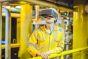 Young woman in a yellow work uniform, glasses and helmet uses virtual reality glasses in industrial environment, oil