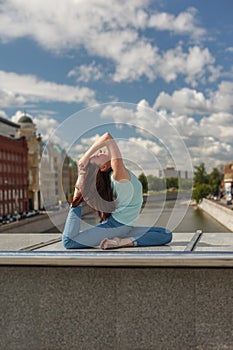 Young woman in a yoga bend pose on a bridge