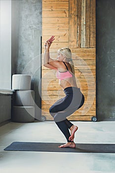 Young woman in yoga class, eagle pose asana