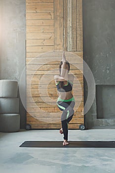 Young woman in yoga class, eagle pose asana