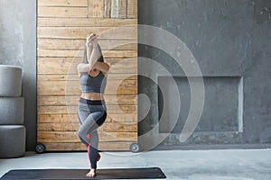 Young woman in yoga class, eagle pose asana, copy space