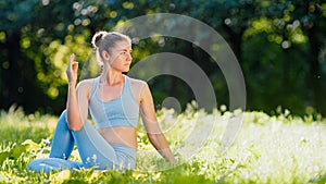 Young woman yoga practitioner in blue tracksuit changes relaxation poses on green grass