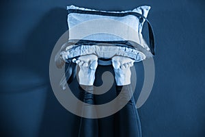 Young woman in yoga relaxing pose with legs up against wall with heavy sand bags