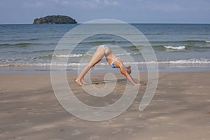 Young woman yoga on sand beach. Tropical seaside vacation activity. Young girl fitness and stretch.