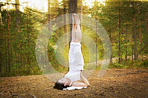 Young woman in Yoga shoulder stand in forest