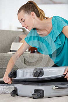 Young woman zipping suitcase