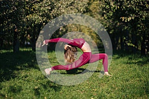 Young womanin red sportswear doing yoga warrior pose in the autumn park