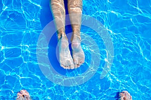 Young womans legs in swimming pool. Summer heat.