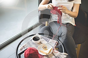 Young womanâ€™s hands knitting warm sweaters. Sitting on old armchair near window, relaxing concept in her bedroom