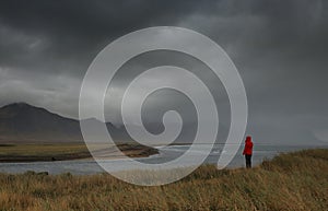 Young women on the Atlantic shore in a stormy weather, in Iceland.
