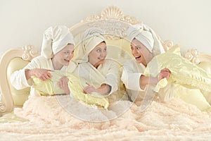 Young women in bathrobes om bed at home