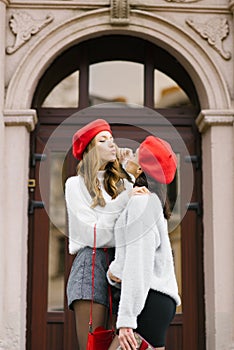 young women in berets blow each other a kiss