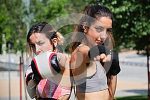 Young women in boxing gloves hitting and looking at camera