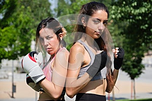 Young women in boxing gloves ready to fight and looking at camera