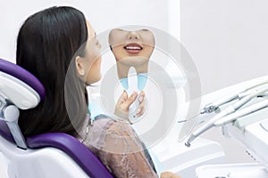 Young women checks her teeth in the mirror. Young woman in the dentists office