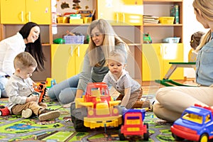 Young women communicate while their kids playing with toys in daycare