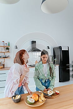 Two girlfriends cut fruit in the kitchen