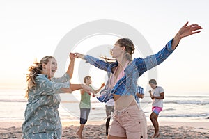 Young women dance on the beach at sunset, with copy space