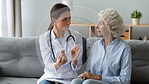 Female nurse prescribe pills to sick senior woman photo