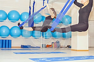 Young women doing aerial yoga exercise or antigravity yoga