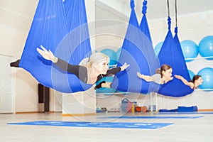 Young women doing aerial yoga exercise or antigravity yoga