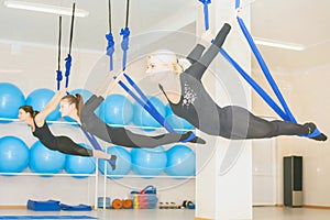 Young women doing aerial yoga exercise or antigravity yoga