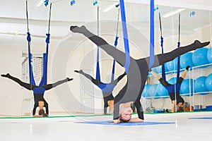 Young women doing aerial yoga exercise or antigravity yoga