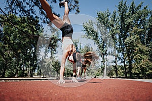 Young women doing cartwheels and stretching in a park, promoting an active lifestyle and enjoying nature.