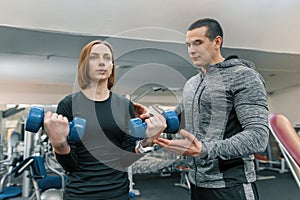 Young woman doing exercises with personal instructor in gym. Sport, athlete, training, healthy lifestyle and people concept