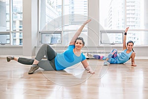 Young women doing workout in gym class indoors to loose weight