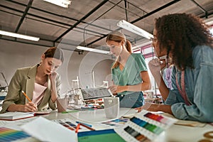 Young women dressmakers work at table in atelier