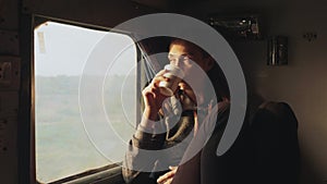 Young women drinking water while looking out of a asian train window