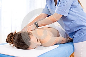 Young woman enjoying therapeutic back massage in physiotherapy session, closeup background.