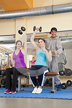 Young women exercising in gym with trainer