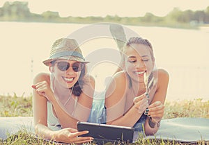 Young women friends laughing watching social media blogs on pad computer