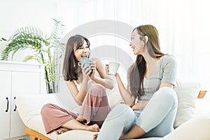 Young women friends talking to each other on a couch at home