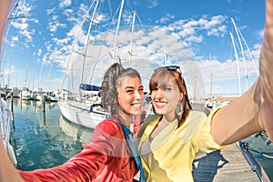 Young women girlfriends taking summer selfie at harbour docks