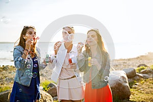 Young women or girls blowing bubbles on beach