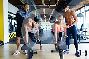 Young women in gym doing exercises with trainers