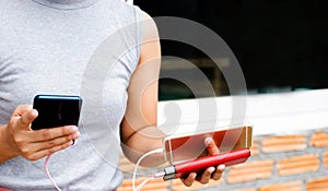 Young women hands holding and playing smartphone While charging the smartphone battery and device Charge Sharing