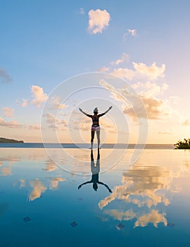 Young women with hands up at Saint Lucia Caribean, women at infinity pool during sunset