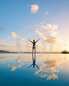 Young women with hands up at Saint Lucia Caribean, women at infinity pool during sunset