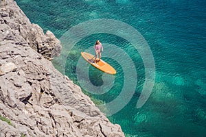 Young women Having Fun Stand Up Paddling in blue water sea in Montenegro. SUP. girl Training on Paddle Board near the