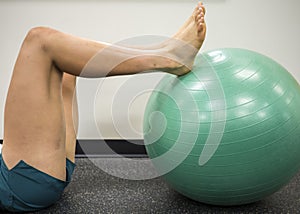 Young women with her feet up on a green exercise ball