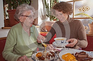 Young woman and her happy grandmother having lunch at restaurant