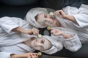 Young women holding slices of cucumber for face care