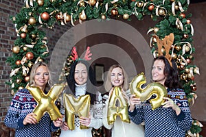 Young women holding word xmas made of golden balloons
