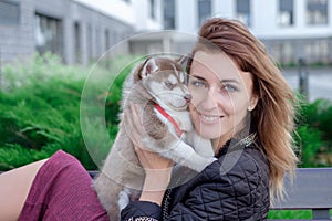 Young women holds her best friend little pet puppy of husky in her arms. love for dogs