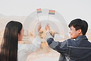 Young women lesbian couple holding a LGBT pride flag . LGBT equal rights concept