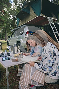 Young women looking road map with vehicle on background